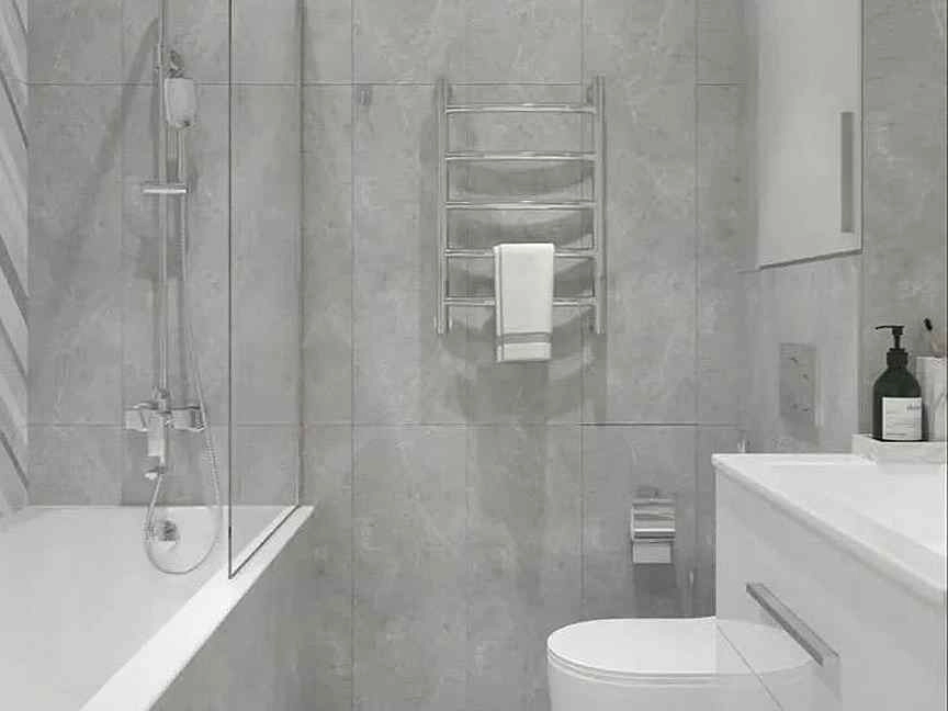 Modern bathroom with green diagonal shower wall tile, terrazzo floor, wood vanity, and black fixtures