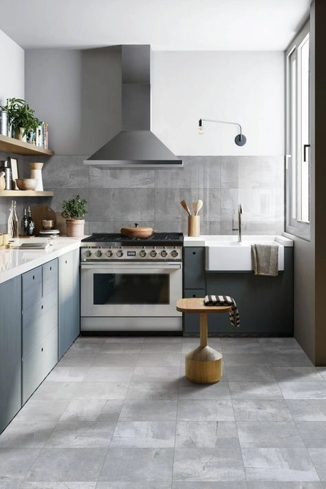 Small kitchen with light gray stone-look floor tile, blue-gray lower cabinets, and farmhouse sink